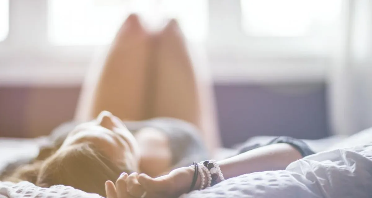 Mulher cansada sentada no sofá segurando uma xícara de chá